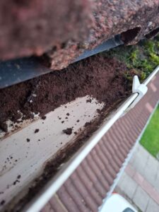 Dirt being removed from white gutter.
