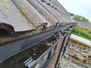View of gutter half way through cleaning with remaining dirt.