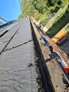 Wide angle view of guttering running along back of terraced property after being cleaned thoroughly.
