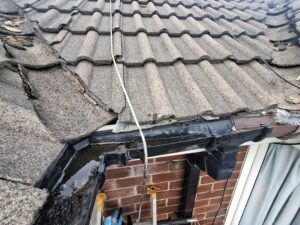 Top view of corner guttering and downspout blocked with stagnant water pooling.