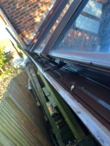View down length of conservatory guttering against boundary wooden fence.